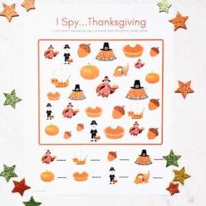 Thanksgiving I Spy printable sitting on table with orange and brown stars scattered on table around printable.