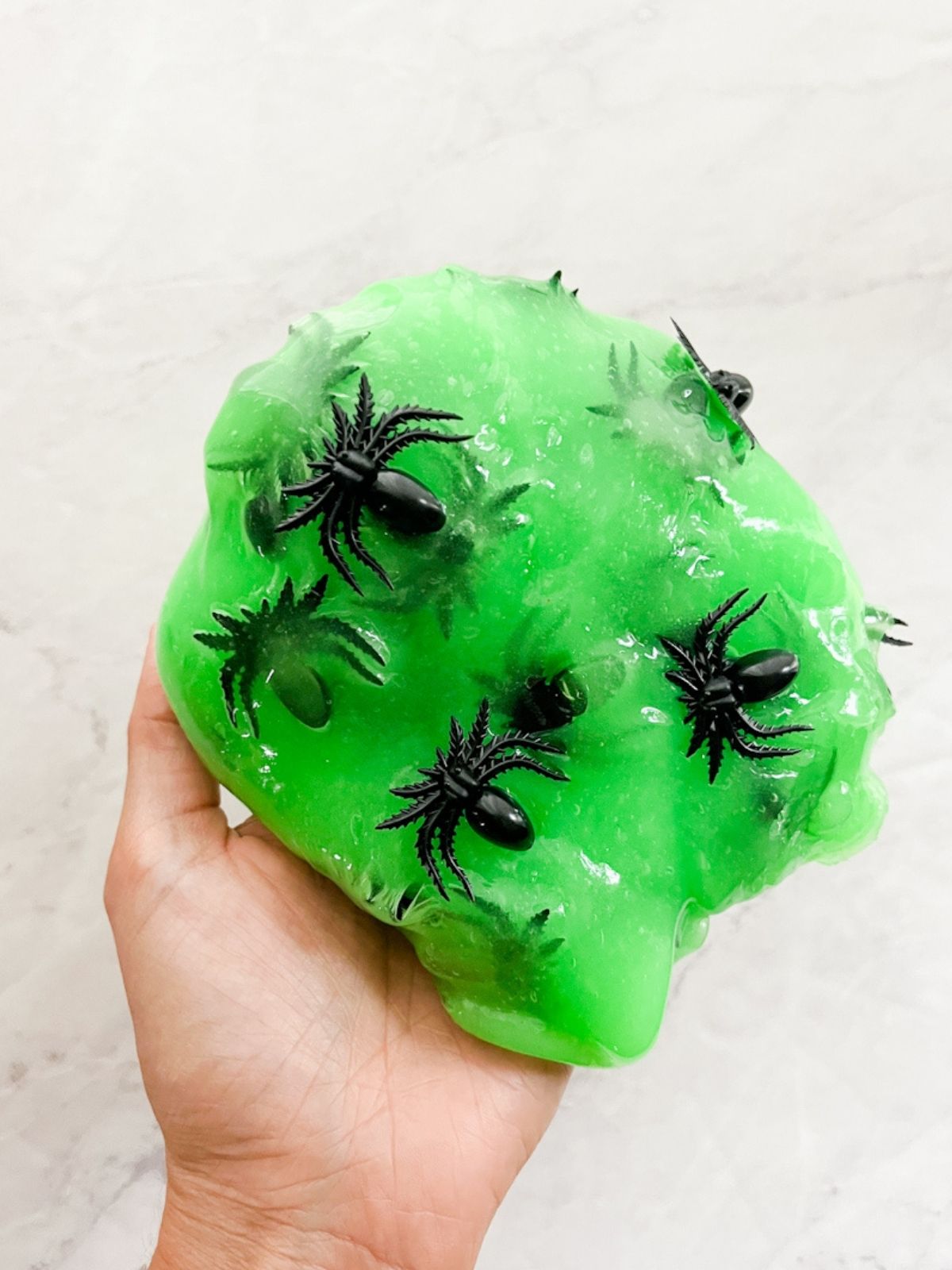 Hand holding green slime with spiders in it.