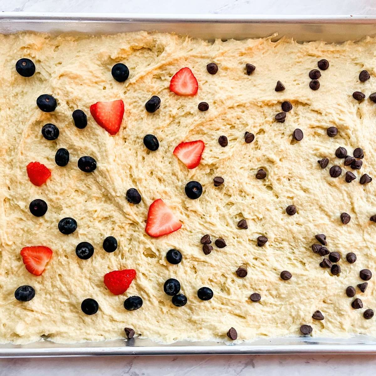 The batter spread evenly on a sheet pan with the toppings on top.